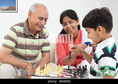 Alter Mann spielt Schach mit seinem Enkel zu Hause Stockfoto