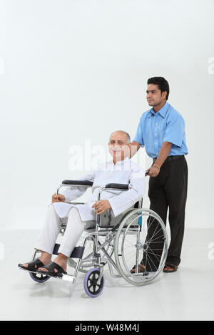 Ward junge einen älteren Mann auf einen Rollstuhl schieben Stockfoto