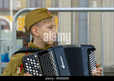 Moskau, Russland - Mai 9, 2019: Unsterbliche regiment Prozession in der Tag des Sieges, ein Soldat Kid spielen Akkordeon durch die künstliche Lagerfeuer Stockfoto