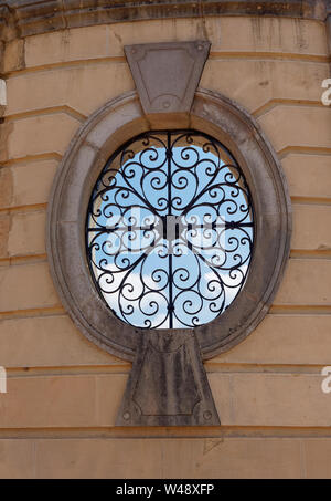 Eine von mehreren Oval geöffnete Fenster in der Palace Wände, durch dekorative cast Schmiedearbeiten am Estoi Palace Hotel in Estoi, Portugal geschützt. Stockfoto