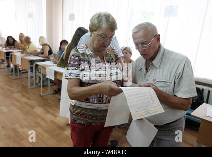 Untersuchen Sie die Wähler einen Stimmzettel im Wahllokal während der Parlamentswahlen in Kiew. Snap Wahlen zum ukrainischen Parlament wird am 21. Juli 2019 abgehalten werden. Ursprünglich geplant Ende Oktober abgehalten werden, diese Wahlen waren nach neu eröffnet Präsident Wladimir Zelensky Parlament am 21. Mai 2019 aufgelöst, während seiner Einweihung gebracht. Stockfoto