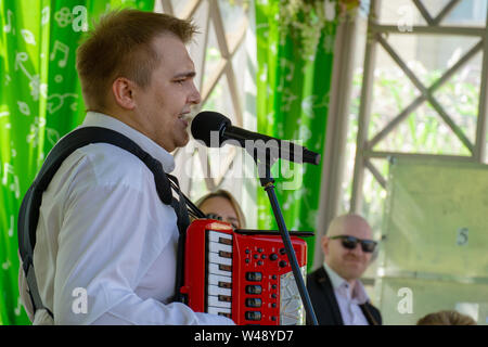 Moskau, Russland - Mai 9, 2019: Mann im weißen Hemd spielt Akkordeon und Gesang Stockfoto