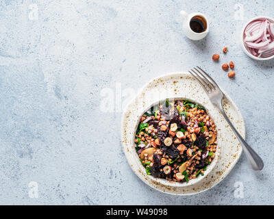 Warme Buchweizen und Rote-Bete-Salat auf grauem Hintergrund. Vegetarische Ernährung Idee und Rezept-Salat mit roter Bete, Buchweizen, Champignons, Zwiebeln, frischen Kräutern, Haselnuss. Ansicht von oben oder flach-legen. Kopieren Sie Platz für Text Stockfoto