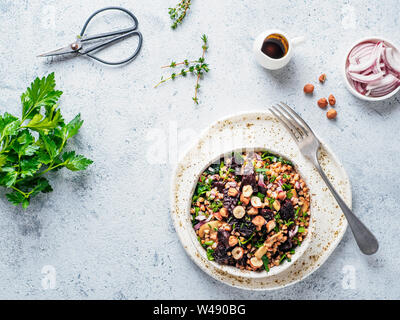 Warme Buchweizen und Rote-Bete-Salat auf grauem Hintergrund. Vegetarische Ernährung Idee und Rezept-Salat mit roter Bete, Buchweizen, Champignons, Zwiebeln, frischen Kräutern, Haselnuss. Ansicht von oben oder flach-legen. Kopieren Sie Platz für Text Stockfoto