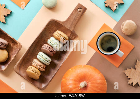 Makronen und Espresso, flach auf geometrische Papier Hintergrund in Pastelltönen mit Herbst Dekorationen legen Stockfoto