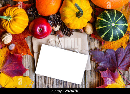 Leere Grußkarte und Umschlag mit Thanksgiving Herbst Hintergrund im Rahmen des geernteten Kürbisse, Äpfel, Nüsse und Ahornblätter auf rustikalem Holz Stockfoto