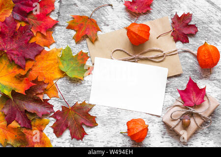 Leere Grußkarte und Geschenkverpackung mit bunten Blätter im Herbst und physalis Blumen auf weißem Holz- Hintergrund. Ansicht von oben mit der Kopie Raum Stockfoto