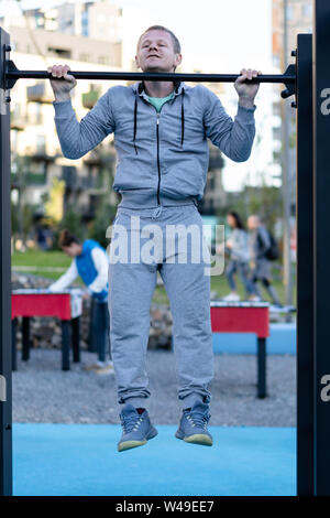 Freizeitaktivitäten. Ein junger Mann zieht sich bis auf eine Bar auf dem Sportplatz im Hof. Stockfoto