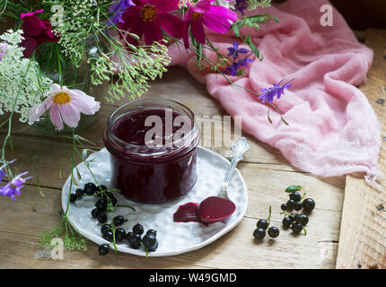 Schwarze Johannisbeere Custard, Korinthen und einen Strauß Blumen auf einem hölzernen Hintergrund. Im rustikalen Stil. Stockfoto