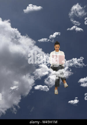 Geschäftsfrau, die auf Wolken sitzt und einen Laptop benutzt Stockfoto