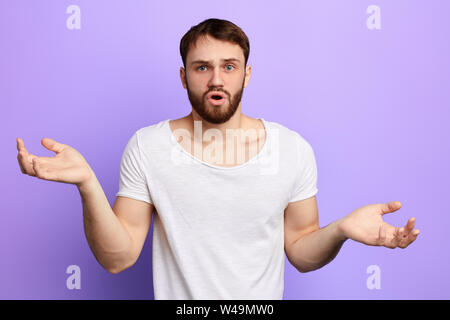Überrascht, stattlicher Mann zuckte mit den Schulter, während die Kamera posieren. nach oben Porträt schließen, isolierte blauen Hintergrund. Emotion und Gefühl, puzzlemen Stockfoto