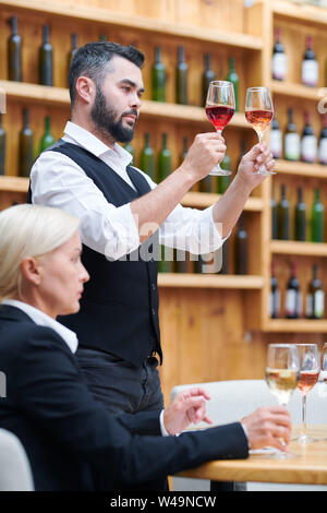 Ein zeitgenössischer Sommeliers vergleich Farben Wein in zwei Gläser Stockfoto