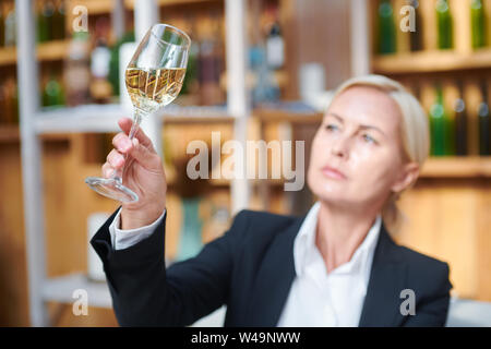 Weibliche Hand bokal mit weißen Wein, während der Prüfung seine Farbe Stockfoto