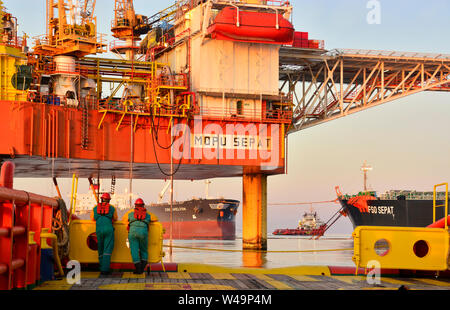 Mannschaft Arbeiten an Deck während der Übertragung öl Plattform persönliche zum Schiff durch Sicherheit Warenkorb betätigen, indem Kranführer Stockfoto