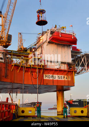 Mannschaft Arbeiten an Deck während der Übertragung öl Plattform persönliche zum Schiff durch Sicherheit Warenkorb betätigen, indem Kranführer Stockfoto