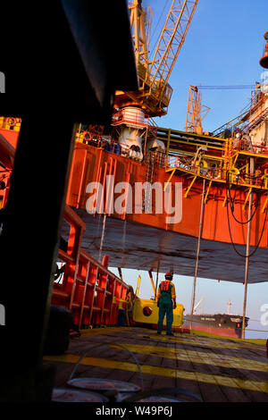 Mannschaft Arbeiten an Deck während der Übertragung öl Plattform persönliche zum Schiff durch Sicherheit Warenkorb betätigen, indem Kranführer Stockfoto