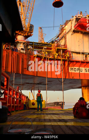 Mannschaft Arbeiten an Deck während der Übertragung öl Plattform persönliche zum Schiff durch Sicherheit Warenkorb betätigen, indem Kranführer Stockfoto