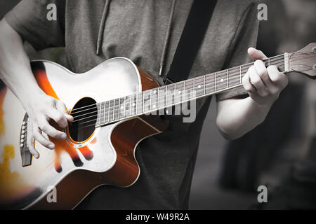 Ein professioneller Musiker spielt eine improvisierte Melodie auf einer 6-String Acoustic Gitarre, halten ein Mediator in seiner Hand. Foto in Schwarz und Weiß Stockfoto