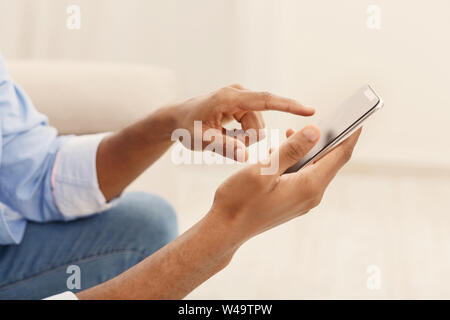 Junger Mann mit modernen Smartphone zu Hause Stockfoto