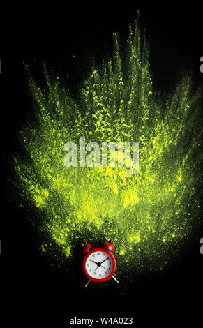 Rot Wecker mit gelben Holi Pulverexplosion auf Schwarz Stockfoto