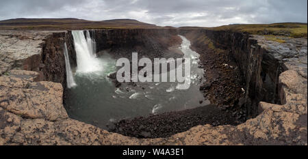 Majestätischer Wasserfall, der in den zerklüfteten Canyon mündet, umgeben von schneebedeckten Bergen auf dem Putorana-Plateau, nördlich von Russland, Naturschutzgebiet Putoranskiy. Stockfoto