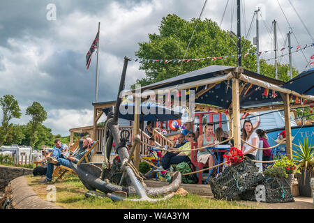 Watermouth Berrynarbor, Hafen, in der Nähe von Ilfracombe, Devon, UK. Sonntag, den 21. Juli 2019. UK Wetter. Trotz der Versammlung cloud Urlauber genießen Sie die langen sonnigen Intervalle und bewundern Sie die Aussicht auf den Hafen von Watermouth sie Erfrischungen an der "Sturm im Wasserglas Cafe'. Credit: Terry Mathews/Alamy leben Nachrichten Stockfoto