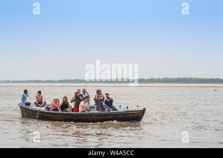 Einige Touristen auf einer Bootsfahrt auf dem Ganges bei Sonnenuntergang. Stockfoto
