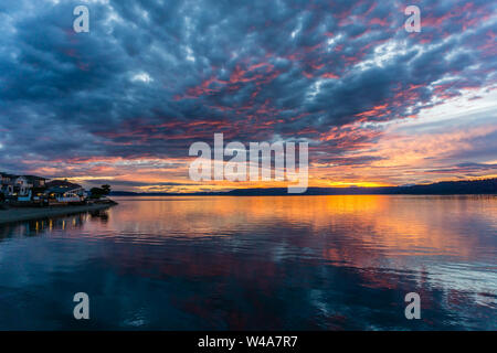 Die Wolken hängen am Himmel, wie die Sonne hinter den Olympic Mountains im Armaturenbrett, Washington. Stockfoto