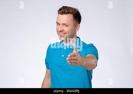Hübscher junger Mann im blauen T-Shirt, die Hand schütteln Stockfoto