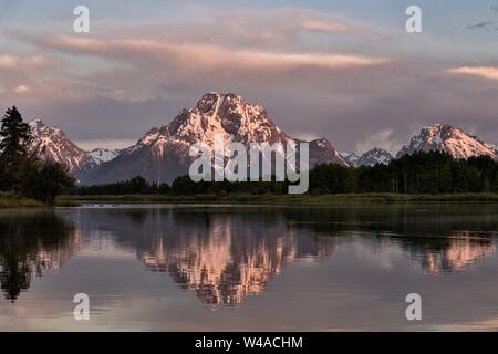 Mount Moran und die Grand Teton Berge auf dem Snake River bei Oxbow Bend in der Dämmerung mit der aufgehenden Sonne auf Wolken im Grand Teton National Park in Moran, Wyoming spiegelt wider. Stockfoto