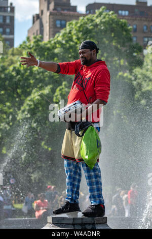 New York, USA - Juni 21, 2019: In einem Brunnen in einem öffentlichen Park, ein schwarzer Mann in rote Kleidung Gesänge. Stockfoto