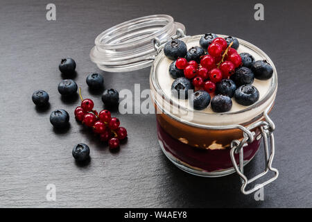 Geschichteten Kuchen Dessert im Glas, Schokolade und Obst Creme, mit Beeren dekoriert. Stockfoto