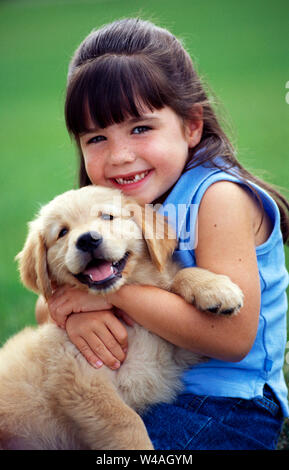 Junge Mädchen dunkel braune Haare mit einem Golden Retriever Welpe Stockfoto