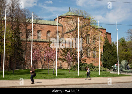 Sofia Bulgarien die St. aus dem 4. Jahrhundert Sophia Ostorthodoxe Kirche mit blühenden Kirschbäumen und Menschen, die am sonnigen Frühlingstag vorbeilaufen, Osteuropa Stockfoto