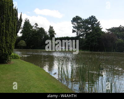 Eine Gruppe von Besuchern eine Führung rund um die seerose Seen bei burnby Hall Gardens; Reflexionen im Wasser zwischen den Seerosen. Stockfoto