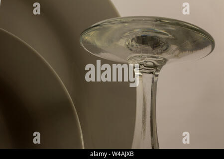 Close-up Details der Basis eines umgekehrten Wein Glas trocknen auf der Abtropffläche neben zwei weißen Platten Stockfoto