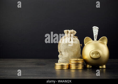 Piggy Bank und Geld Beutel mit Münzen auf dunklem Hintergrund Stockfoto