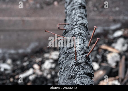 Die schwarz Dirty verkohlten Protokoll der niedergebrannten Haus mit hakt, rostige Nägel Stockfoto
