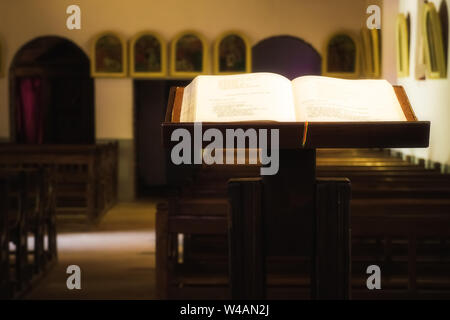 Schön beleuchteten offenen christlichen Bibel auf einem hölzernen Rednerpult in eine Kirche. Stockfoto