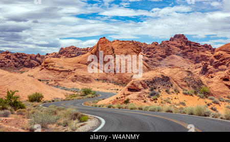 Tal des Feuers highway Nevada, USA. Leere kurvenreiche Straße, vorbei an der amerikanischen Wüste und Tal Red Rocks, Blau bewölkter Himmel Hintergrund Stockfoto