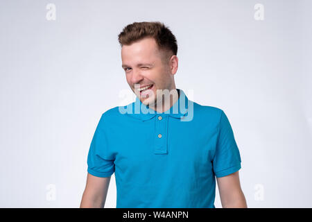 Happy sly Mann im blauen T-Shirt Zwinkern im Auge Stockfoto