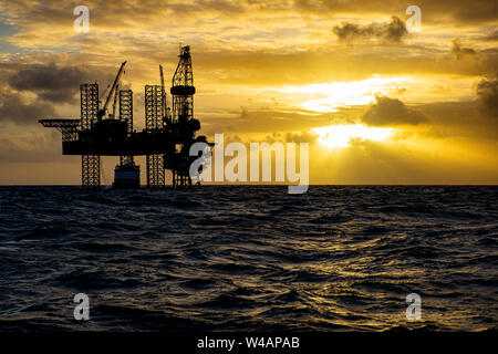 Offshore Bohrinsel bei Sonnenaufgang mit Arbeit Schiff Stockfoto