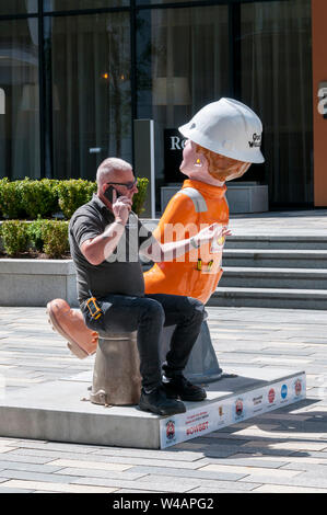 Das Leben ahmt die Kunst als einen Mann auf dem umgedrehten Eimer ein Oor Wullie Statue in Aberdeen sitzt. Stockfoto