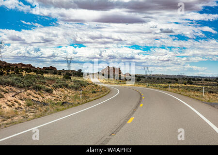 Autobahn an einem sonnigen Frühlingstag, Landschaft der USA. Leere kurvenreiche Straße, vorbei an der amerikanischen Wüste, blauer Himmel mit Wolken Hintergrund Stockfoto