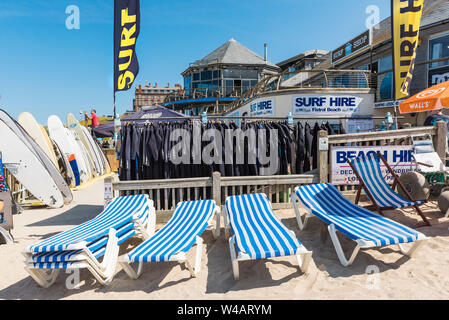 Surfbretter, Neoprenanzüge und Sonnenliegen zum Mieten aus den Fistral Surfen Mietwagen in Newquay in Cornwall zur Verfügung. Stockfoto
