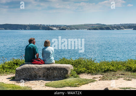 Urlauber auf einen Felsen auf den Towan Kopf Landzunge mit Blick auf die Bucht von Newquay in Cornwall sitzen. Stockfoto