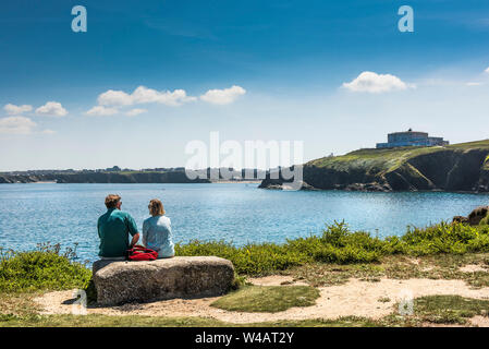 Urlauber auf einen Felsen auf den Towan Kopf Landzunge mit Blick auf die Bucht von Newquay in Cornwall sitzen. Stockfoto