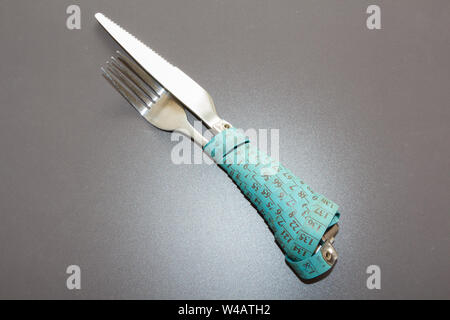 Blau Maßband um eine Gabel und ein Messer als Konzept für Ernährung Stockfoto