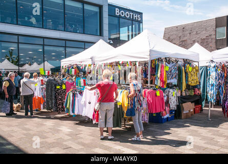 Lady Käufer, um Marktstände mit Kleidung am Markttag in Poulton gefüllt le Fylde Lancashire England Großbritannien Stockfoto