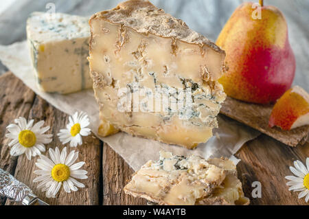 Ein Stück blau gealtert Stilton Käse auf einem Holztisch. Käse ist mit einem schönen reife Birne serviert. Die Qualität der landwirtschaftlichen Produkte der Landwirte. De Stockfoto